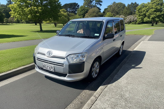 Silver Toyota van parked on a street with buildings in the background